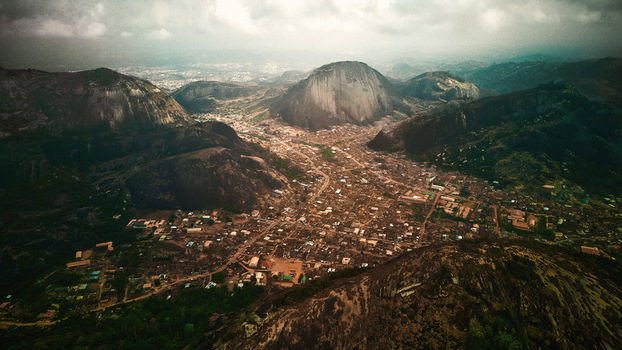 Aerial view of lush green hills interspersed with rocky outcrops and a dense town nestled below a blend of nature and civilization Idanre Ondo Nigeria. Aerial view of lush green hills interspersed with rocky outcrops and a dense town nestled below a blend of nature and civilization Idanre Ondo Nigeria.