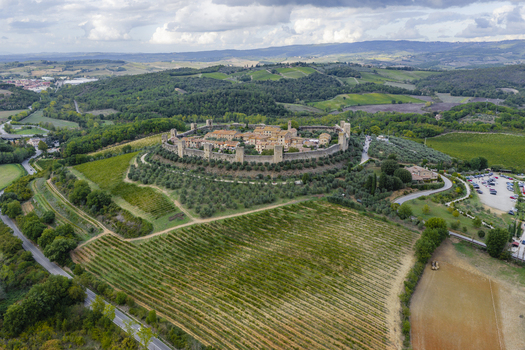 Aerial view of the historic walled town of Monteriggioni surrounded by lush vineyards olive groves and rolling hills in the Tuscan countryside. Monteriggioni Tuscany Italy.