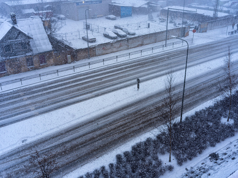 View of a snow covered street with parked cars and buildings during a winter snowfall in Vilnius Vilnius County Lithuania. View of a snow covered street with parked cars and buildings during a winter snowfall in Vilnius Vilnius County Lithuania.