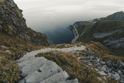 View of the stone steps on the Reinebringen trail overlooking the coastal road sea and rugged mountains in Moskenes Nordland Norway.