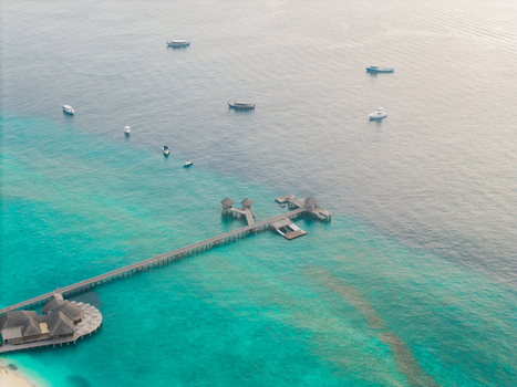 Aerial view of a pier extending into the turquoise sea where boats dance on the horizon Hoarafushi Thiladhunmathee Uthuruburi Maldives. Aerial view of a pier extending into the turquoise sea where boats dance on the horizon Hoarafushi Thiladhunmathee Uthuruburi Maldives.