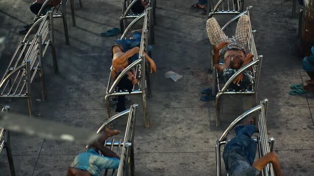 View of people sleeping on metal benches in Dhaka Bangladesh.