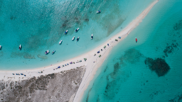 Aerial view of Los Roques archipelago with a narrow white sandbar turquoise waters anchored boats and beach umbrellas Los Roques Dependencias Federale Venezuela. Aerial view of Los Roques archipelago with a narrow white sandbar turquoise waters anchored boats and beach umbrellas Los Roques Dependencias Federale Venezuela.