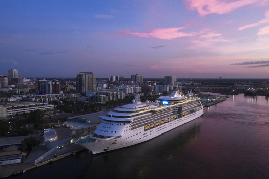 Tampa Florida United States 04 July 2026 Aerial view of Tampa Cruise Terminal 6 with a cruise ship docked at the pier featuring the city skyline under a sunset sky.