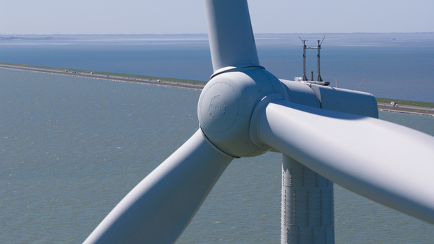 Aerial view of a wind turbine at Windpark Fryslan with the Afsluitdijk causeway stretching across the water in Breezanddijk Friesland Netherlands. Aerial view of a wind turbine at Windpark Fryslan with the Afsluitdijk causeway stretching across the water in Breezanddijk Friesland Netherlands.