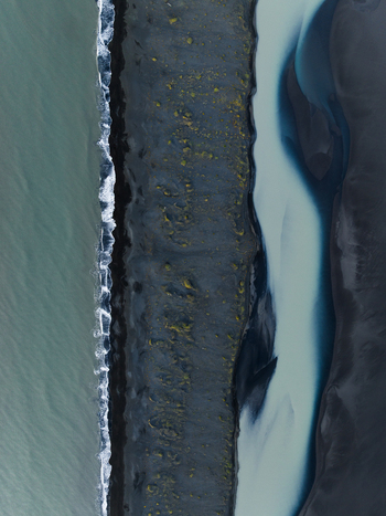 Aerial view of the stark contrast of the black sand beach meeting the turquoise sea with a milky river cutting through the volcanic landscape Iceland Iceland. Aerial view of the stark contrast of the black sand beach meeting the turquoise sea with a milky river cutting through the volcanic landscape Iceland Iceland.