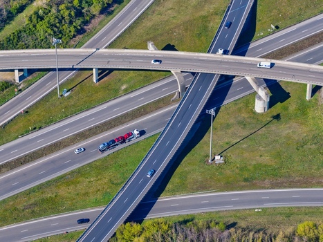 Aerial view of a multilane highway with multiple overpass intersections and sparse vehicles cutting through a green and brown landscape Sausheim Grand Est France.