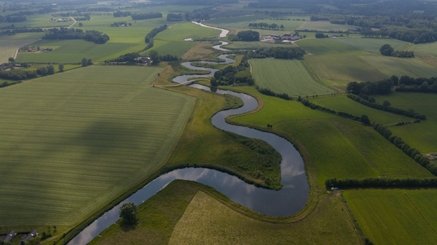 Aerial view of the winding Berkel river flowing through lush green agricultural fields and meadows in the rural landscape of Almen Gelderland Netherlands. Aerial view of the winding Berkel river flowing through lush green agricultural fields and meadows in the rural landscape of Almen Gelderland Netherlands.