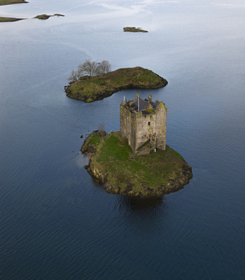 Aerial view of Castle Stalker on a small green islet surrounded by calm blue water and rocky outcrops Appin Scotland United Kingdom. Aerial view of Castle Stalker on a small green islet surrounded by calm blue water and rocky outcrops Appin Scotland United Kingdom.