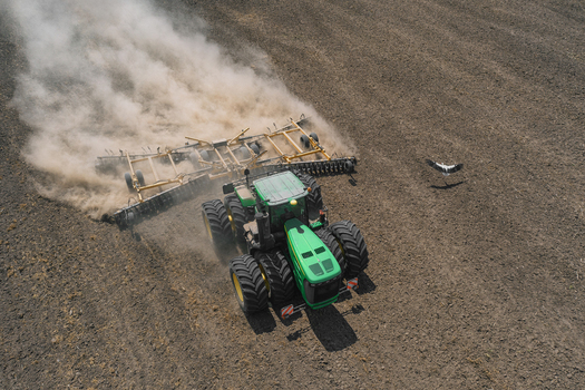 Aerial view of a green tractor tilling the land kicking up dust in stark contrast to the dark soil Chyhyryns kyi district Cherkasy Oblast Ukraine. Aerial view of a green tractor tilling the land kicking up dust in stark contrast to the dark soil Chyhyryns kyi district Cherkasy Oblast Ukraine.