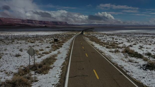 View of a snowy desert road with distant red cliffs United States. View of a snowy desert road with distant red cliffs United States.