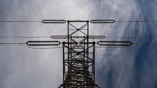 View of high voltage power lines on a metal pylon against a cloudy sky in Iceland.