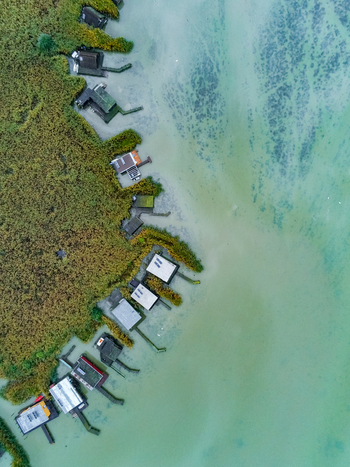 Aerial view of stilt houses nestled among reed beds along the turquoise waters of Lake Neusiedl in Rust Burgenland Austria.