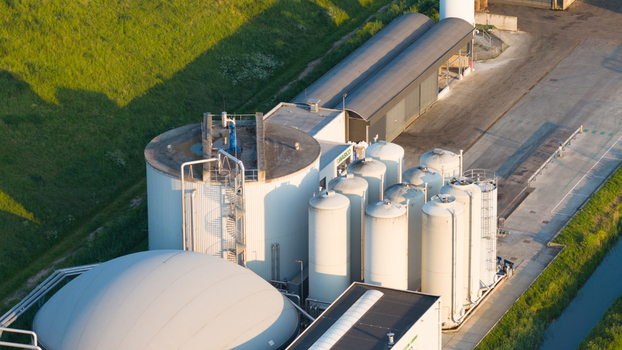 Aerial view of the Wabico BV biogas plant featuring large storage silos and a white dome structure next to a green embankment Waalwijk Noord Brabant Netherlands.