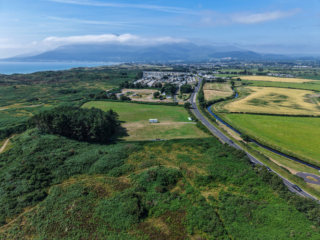 Aerial view of the coastal landscape near the Mourne Mountains with green fields a road and the sea in Newcastle Northern Ireland United Kingdom. Aerial view of the coastal landscape near the Mourne Mountains with green fields a road and the sea in Newcastle Northern Ireland United Kingdom.