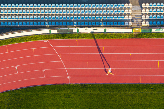 Aerial view of the Sports and Recreation Center featuring a red running track with a person jogging and stadium seating Starogard Gdanski Pomeranian Voivodeship Poland. Aerial view of the Sports and Recreation Center featuring a red running track with a person jogging and stadium seating Starogard Gdanski Pomeranian Voivodeship Poland.
