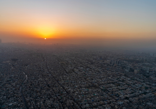 Aerial view of the dense urban sprawl of Karachi at sunset with golden light casting long shadows over the rooftops in Karachi Sindh Pakistan.