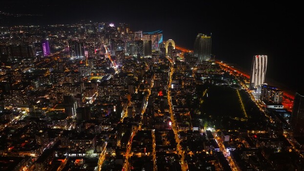 Batumi Adjara Georgia 17 September 2026 Aerial view of the illuminated cityscape at night featuring modern skyscrapers glowing streets and the Black Sea coastline.
