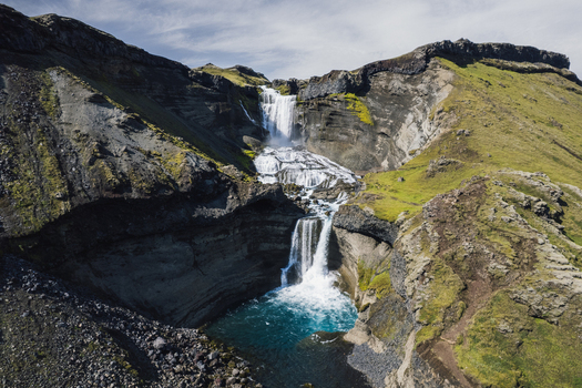 Aerial view of cascading waterfalls plunge into a turquoise pool embraced by rugged cliffs and verdant mossy slopes Ofaerufoss Highlands of Iceland. Aerial view of cascading waterfalls plunge into a turquoise pool embraced by rugged cliffs and verdant mossy slopes Ofaerufoss Highlands of Iceland.