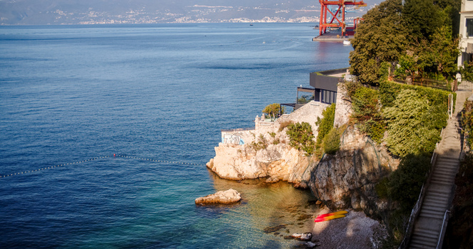 Rijeka Primorje Gorski Kotar Croatia 19 September 2026 View of a modern villa on a rocky cliff overlooking the Adriatic Sea with a small beach kayaks and a distant harbor crane. Rijeka Primorje Gorski Kotar Croatia 19 September 2026 View of a modern villa on a rocky cliff overlooking the Adriatic Sea with a small beach kayaks and a distant harbor crane.