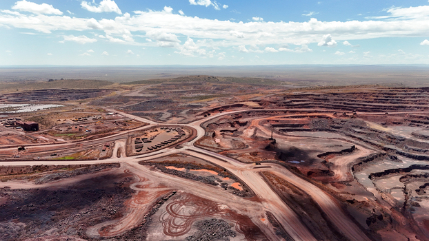 Aerial view of the sprawling scarred landscape of an open pit mine where deep red earth contrasts sharply with the pale blue sky and distant horizons Rustenburg North West South Africa. Aerial view of the sprawling scarred landscape of an open pit mine where deep red earth contrasts sharply with the pale blue sky and distant horizons Rustenburg North West South Africa.