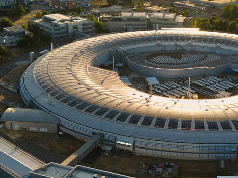 Aerial view of Diamond Light Source a circular synchrotron facility surrounded by greenery under golden hour light in Didcot United Kingdom.