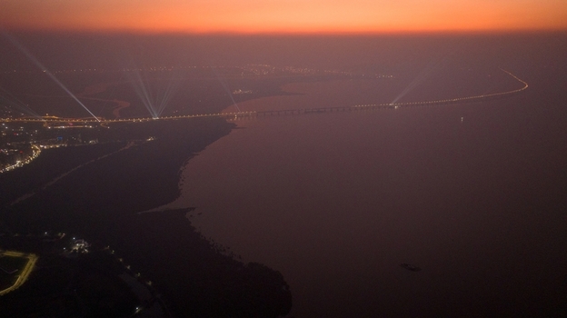 Aerial view of the illuminated bridge stretching across the water at dusk with city lights glowing in the distance Nagda Madhya Pradesh India. Aerial view of the illuminated bridge stretching across the water at dusk with city lights glowing in the distance Nagda Madhya Pradesh India.