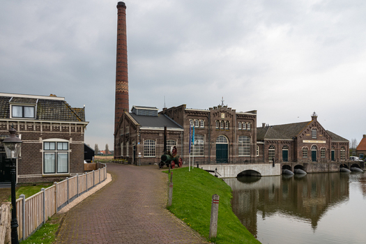 View of the Dutch Steam Engine Museum with its tall brick chimney and historic industrial architecture by the water in Medemblik Noord Holland Netherlands. View of the Dutch Steam Engine Museum with its tall brick chimney and historic industrial architecture by the water in Medemblik Noord Holland Netherlands.