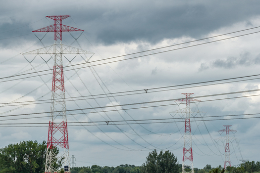 Aerial view of high voltage power transmission towers with red and white lattice structures set against a cloudy sky in Poland. Aerial view of high voltage power transmission towers with red and white lattice structures set against a cloudy sky in Poland.