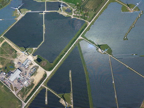 Aerial view of Chelveston Wind Farm featuring vast rows of solar panels and wind turbines across green fields in Wellingborough England United Kingdom. Aerial view of Chelveston Wind Farm featuring vast rows of solar panels and wind turbines across green fields in Wellingborough England United Kingdom.