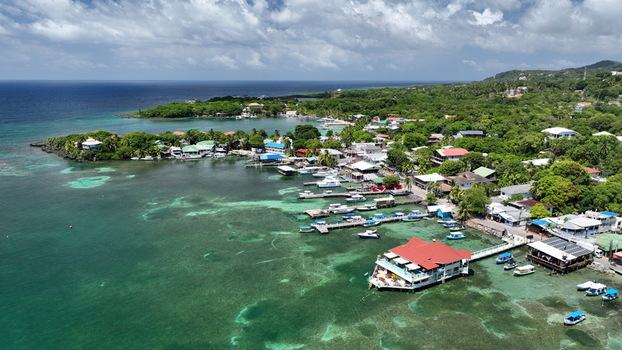 Aerial view of the coastal village of West End featuring turquoise waters wooden docks boats and lush tropical vegetation in West End Bay Islands Department Honduras. Aerial view of the coastal village of West End featuring turquoise waters wooden docks boats and lush tropical vegetation in West End Bay Islands Department Honduras.