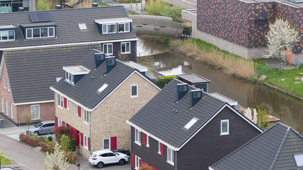 Aerial view of modern residential houses with dark tiled roofs and a small canal in Almere Flevoland Netherlands. Aerial view of modern residential houses with dark tiled roofs and a small canal in Almere Flevoland Netherlands.