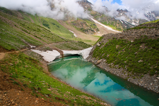 View of the turquoise waters of Rama Lake surrounded by snow capped mountains green meadows and rocky slopes in Astore Gilgit Pakistan. View of the turquoise waters of Rama Lake surrounded by snow capped mountains green meadows and rocky slopes in Astore Gilgit Pakistan.