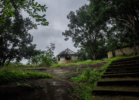 View of a dilapidated hut with a damaged roof nestled among trees on a rocky slope with stone steps in Jos Plateau Nigeria. View of a dilapidated hut with a damaged roof nestled among trees on a rocky slope with stone steps in Jos Plateau Nigeria.