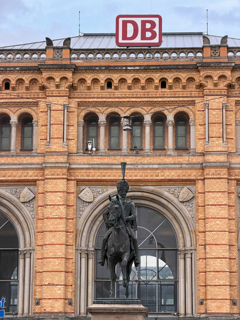 Hanover Germany 29 March 2026 View of the Ernst August monument in front of the historic brick facade of the Hanover main railway station with the Deutsche Bahn logo.