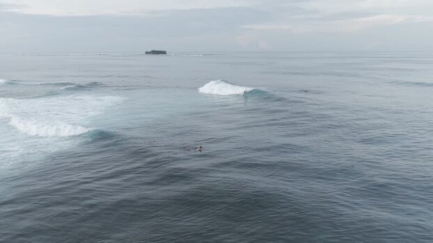Aerial view of surfers riding waves at Siargao Island Philippines.