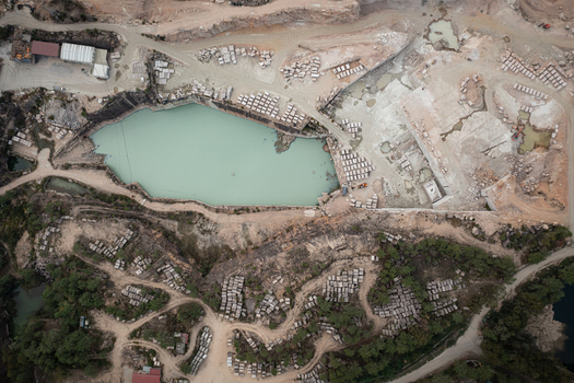Aerial view of Cantera Porrino a granite quarry featuring a turquoise water pool stone blocks and industrial excavation patterns in O Porrino Pontevedra Spain. Aerial view of Cantera Porrino a granite quarry featuring a turquoise water pool stone blocks and industrial excavation patterns in O Porrino Pontevedra Spain.