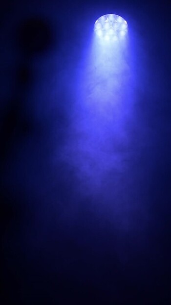 View of a blue spotlight beaming through thick smoke.
