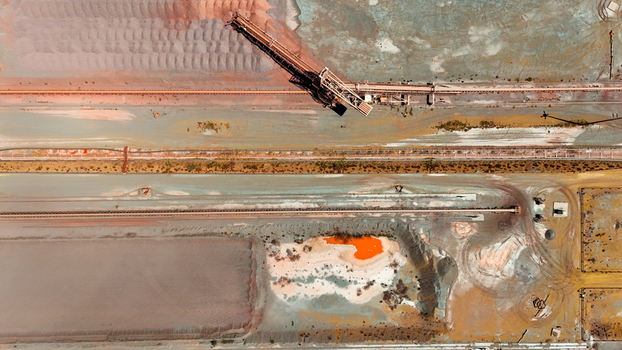 Aerial view of a sprawling industrial site with a conveyor belt vibrant orange pools and diverse earth tones Rustenburg North West South Africa. Aerial view of a sprawling industrial site with a conveyor belt vibrant orange pools and diverse earth tones Rustenburg North West South Africa.