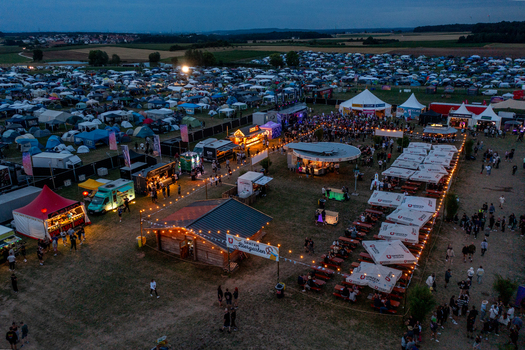 Herzogenaurach Germany 25 July 2025 Aerial view of Open Beatz Festival campsite with numerous tents food stalls and people gathered under the evening sky. Herzogenaurach Germany 25 July 2025 Aerial view of Open Beatz Festival campsite with numerous tents food stalls and people gathered under the evening sky.