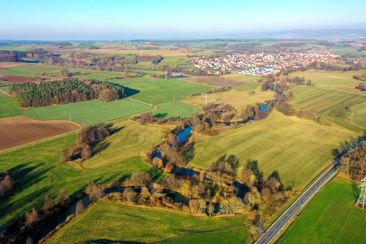 Aerial view of the winding Aisch river flowing through green meadows and agricultural fields near the village of Uehlfeld Bayern Germany. Aerial view of the winding Aisch river flowing through green meadows and agricultural fields near the village of Uehlfeld Bayern Germany.