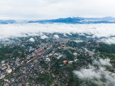 Aerial view of the city of Kandy nestled among lush green hills and covered by a thick layer of white clouds under an overcast sky Kandy Central Province Sri Lanka. Aerial view of the city of Kandy nestled among lush green hills and covered by a thick layer of white clouds under an overcast sky Kandy Central Province Sri Lanka.