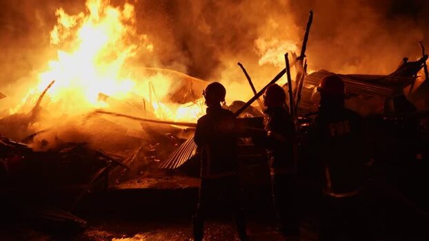 View of firefighters battling a large fire at night Bangladesh. View of firefighters battling a large fire at night Bangladesh.
