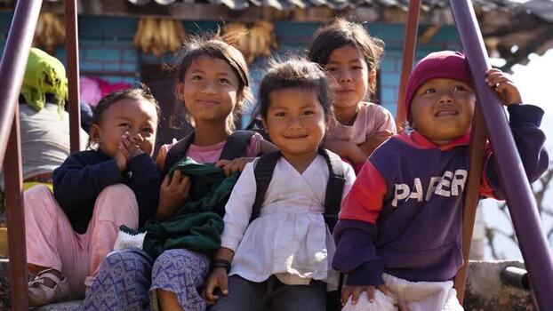 View of a group of smiling children sitting on stairs Nepal.