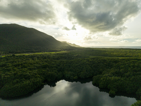 Aerial view of sunlight filtering through the clouds over lush mangrove forests and calm waters Karimunjawa Central Java Indonesia.