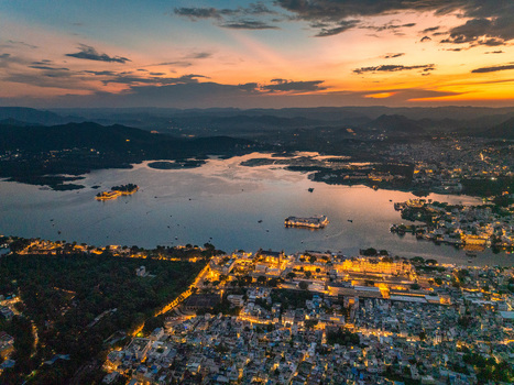 Aerial view of Lake Pichola with the illuminated Lake Palace and Jag Mandir surrounded by the city lights of Udaipur at sunset in Udaipur Rajasthan India.