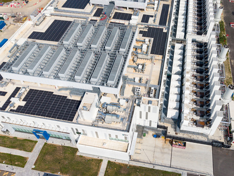 Aerial view of a modern hyperscale data center featuring extensive rooftop solar panels cooling units and industrial infrastructure in Melegnano Lombardy Italy.
