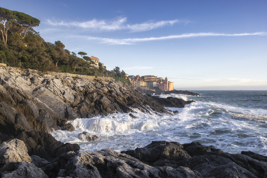 View of the historic village of Tellaro perched on a rocky cliff with waves crashing against the shore under a clear blue sky in Tellaro Liguria Italy. View of the historic village of Tellaro perched on a rocky cliff with waves crashing against the shore under a clear blue sky in Tellaro Liguria Italy.