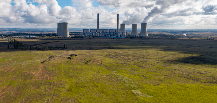 Aerial view of the power station with cooling towers and smoking chimneys across vast fields under a cloudy sky in Vaal Power Small Holdings Free State South Africa. Aerial view of the power station with cooling towers and smoking chimneys across vast fields under a cloudy sky in Vaal Power Small Holdings Free State South Africa.
