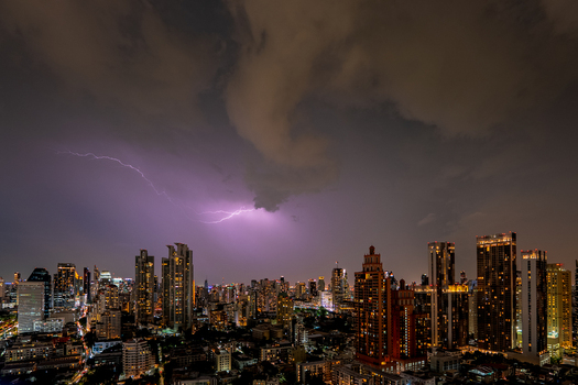 View of a lightning strike illuminating the night sky over the modern skyscrapers and urban skyline of Bangkok Bangkok Thailand.